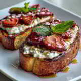 Fresh strawberry ricotta toast with golden sourdough, drizzled honey, and mint garnish, perfect for a vibrant brunch spread.