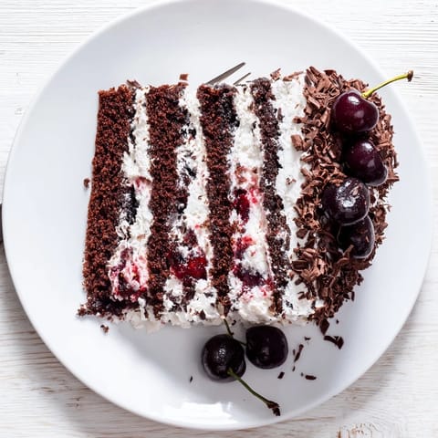 Freshly baked Black Forest Cake slices showcase moist chocolate layers and vibrant cherry filling on a white plate.