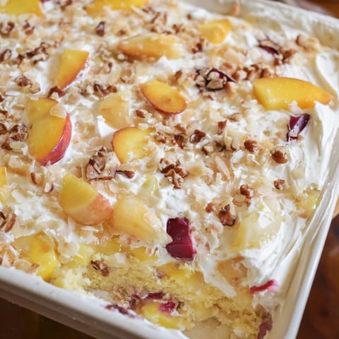 Golden brown Fruit Cocktail Cake with coconut frosting in a baking pan, topped with shredded coconut.