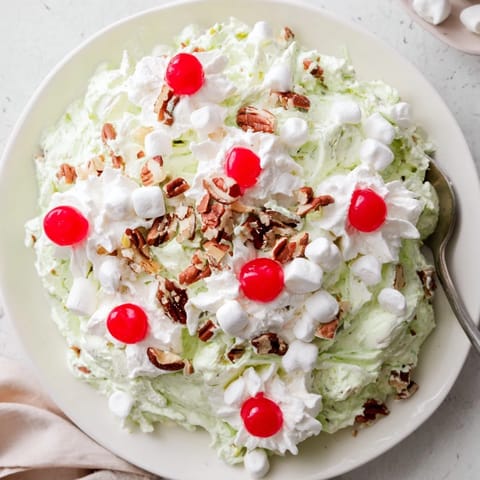 A spoon scoops creamy Watergate Salad with fluffy marshmallows and crushed pineapple, ideal for a summer potluck.