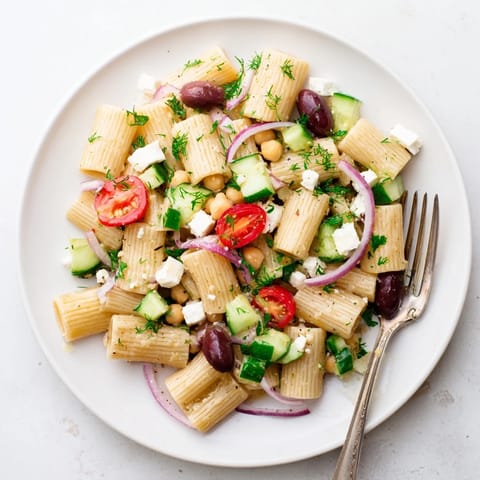 A refreshing, protein-packed Lemon Herb Chickpea Pasta Salad for a light summer lunch, garnished with crumbled feta and kalamata olives for a Mediterranean twist.  