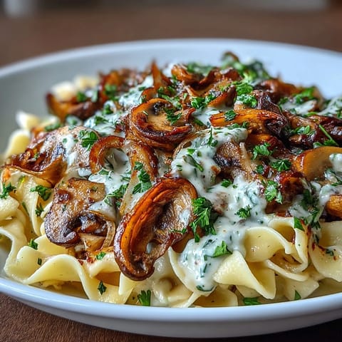 Creamy onion and mushroom stroganoff served over a bed of tender egg noodles, garnished with fresh parsley.  
