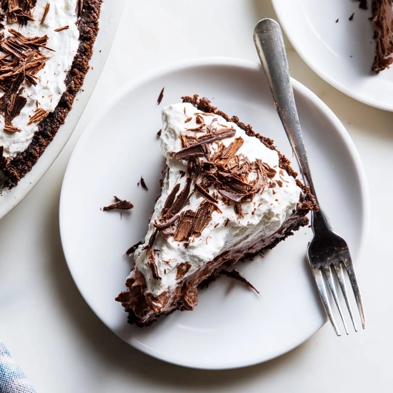A slice of Mississippi Mud Pie revealing the brownie base and creamy chocolate filling, served on a rustic wooden table.