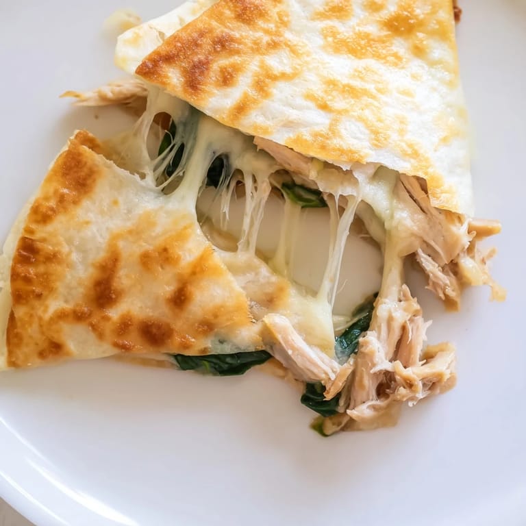 Freshly grilled Chicken and Spinach Quesadilla cut into wedges, revealing melted mozzarella, tender spinach, and seasoned chicken inside.