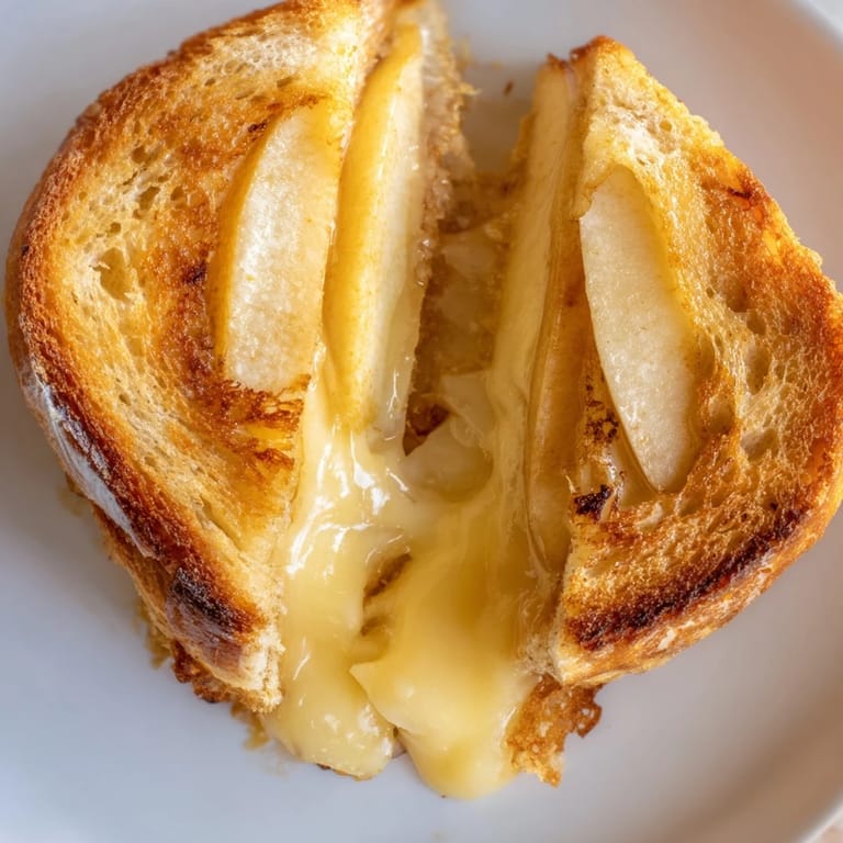 Steaming, sliceable Smoked Gouda & Apple Grilled Cheese on a plate, perfect for lunch.