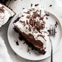 Fudgy Mississippi Mud Pie with a rich chocolate pudding layer, fluffy whipped cream, and chocolate shavings on a dessert plate.