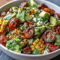 A vibrant summer salad with sweet corn, juicy tomatoes, creamy avocado, and a tangy lime vinaigrette, perfect for warm days.