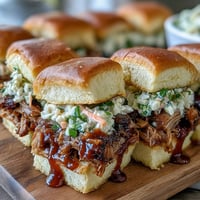 Pulled pork sliders with coleslaw, piled high on soft buns, perfect for baby shower parties and festive gatherings.  
