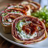 Vibrant Italian sub pinwheel wraps with layers of deli meats, cheese, and roasted peppers, rolled in flour tortillas for a party-ready appetizer.